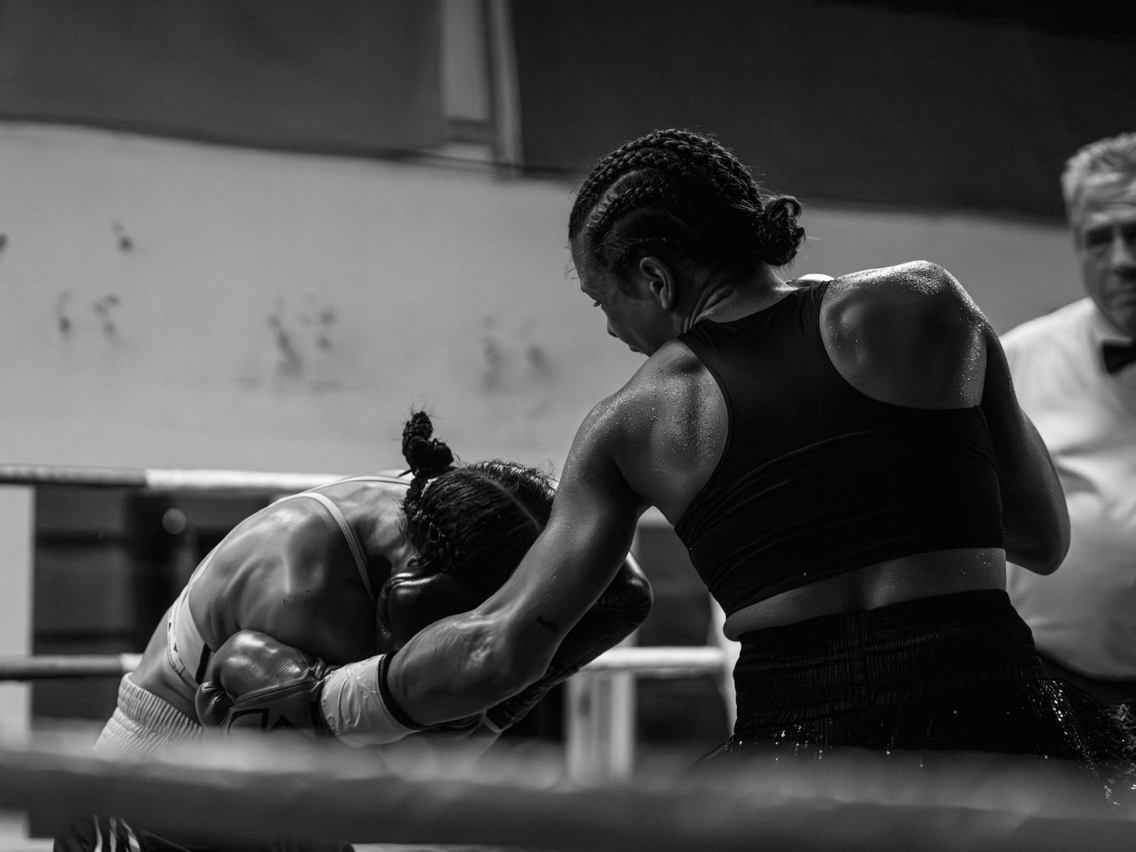 Compétition de boxe anglaise Boxing Center — deux boxeuses au corps à corps sur le ring, un soir de gala