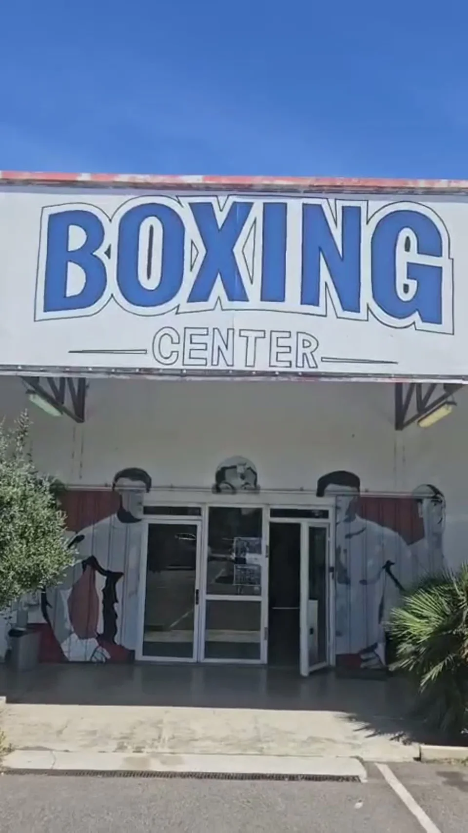 La façade du Boxing Center au 61 route d’Espagne à Portet-sur-Garonne : le nom du club en lettres bleues sur le mur blanc et des boxeurs peints autour de la porte vitrée